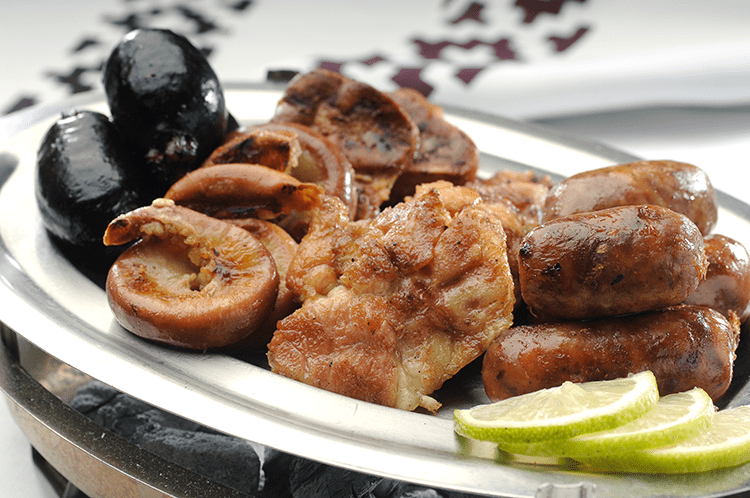 Achuras including chorizo and morcilla on a grill