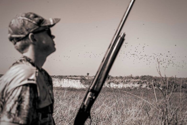 Hunter watching hundreds of doves flying during a dove hunting experience at C&C Outfitters' Alijilan Lodge in Tucumán, Argentina